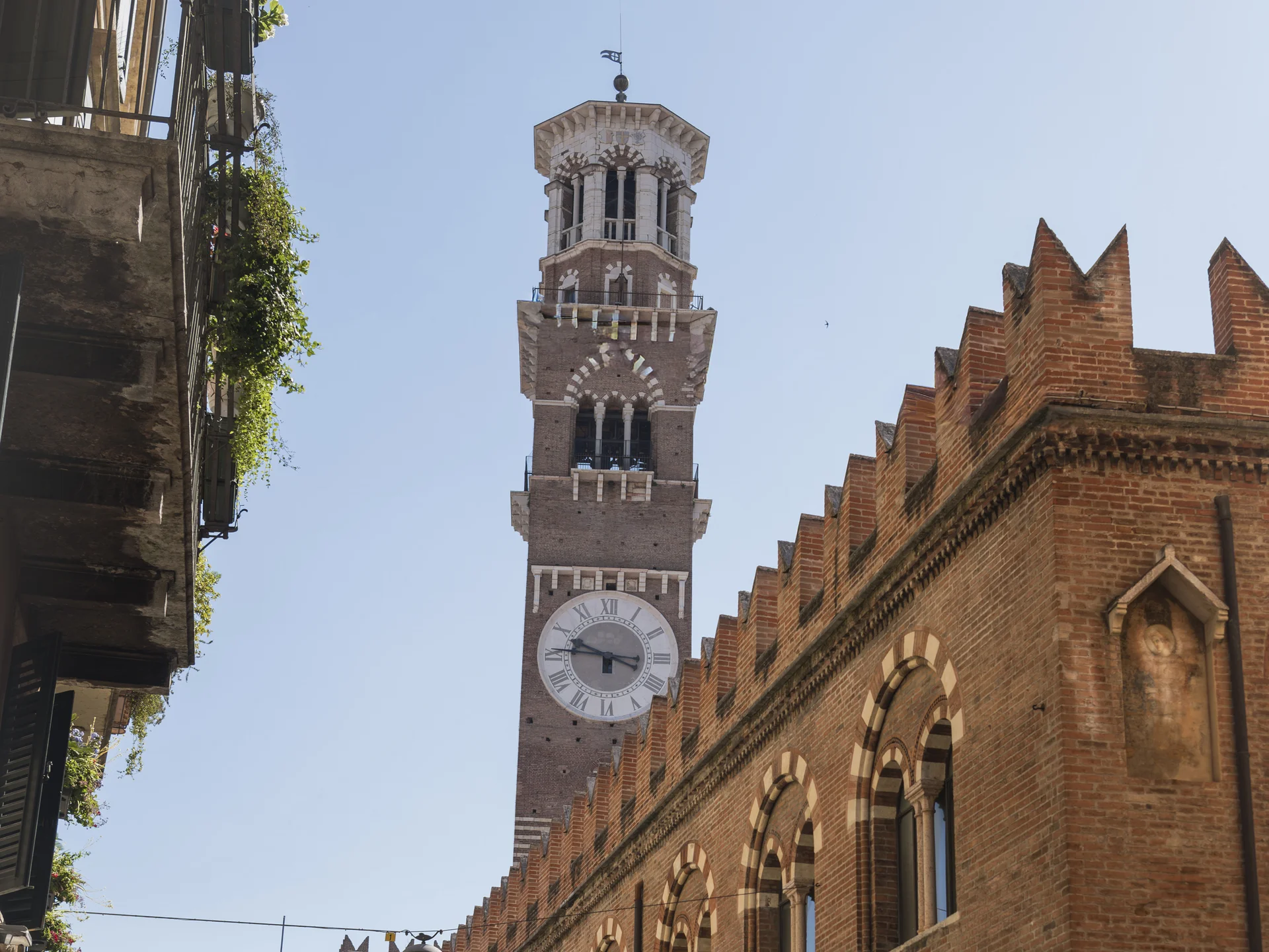 Hotels near the Arena di Verona, Italy | Touring Vista della torre dell'orologio e edificio storico in mattoni con archi a Verona