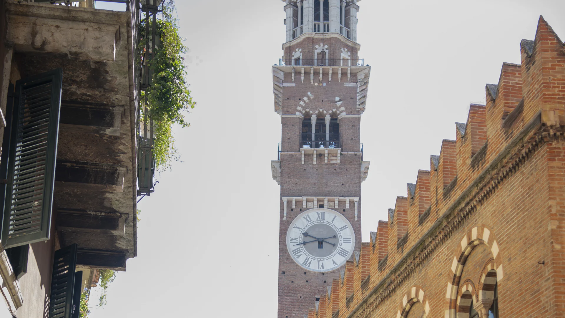Hotel Touring in Verona | Picture gallery Torre con orologio e edificio storico con archi in una strada cittadina