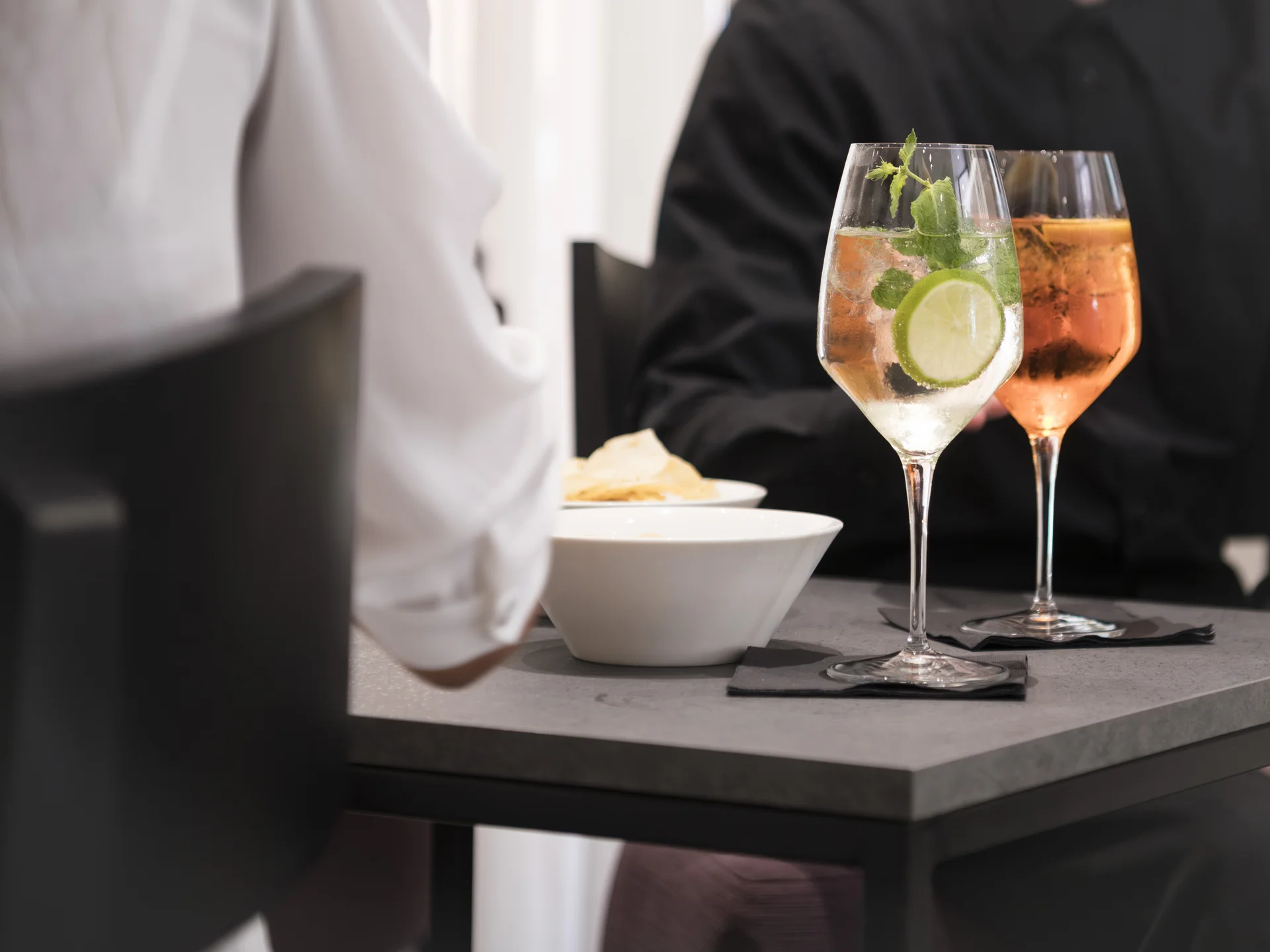 Due cocktail in bicchieri da vino su un tavolo con due persone sedute