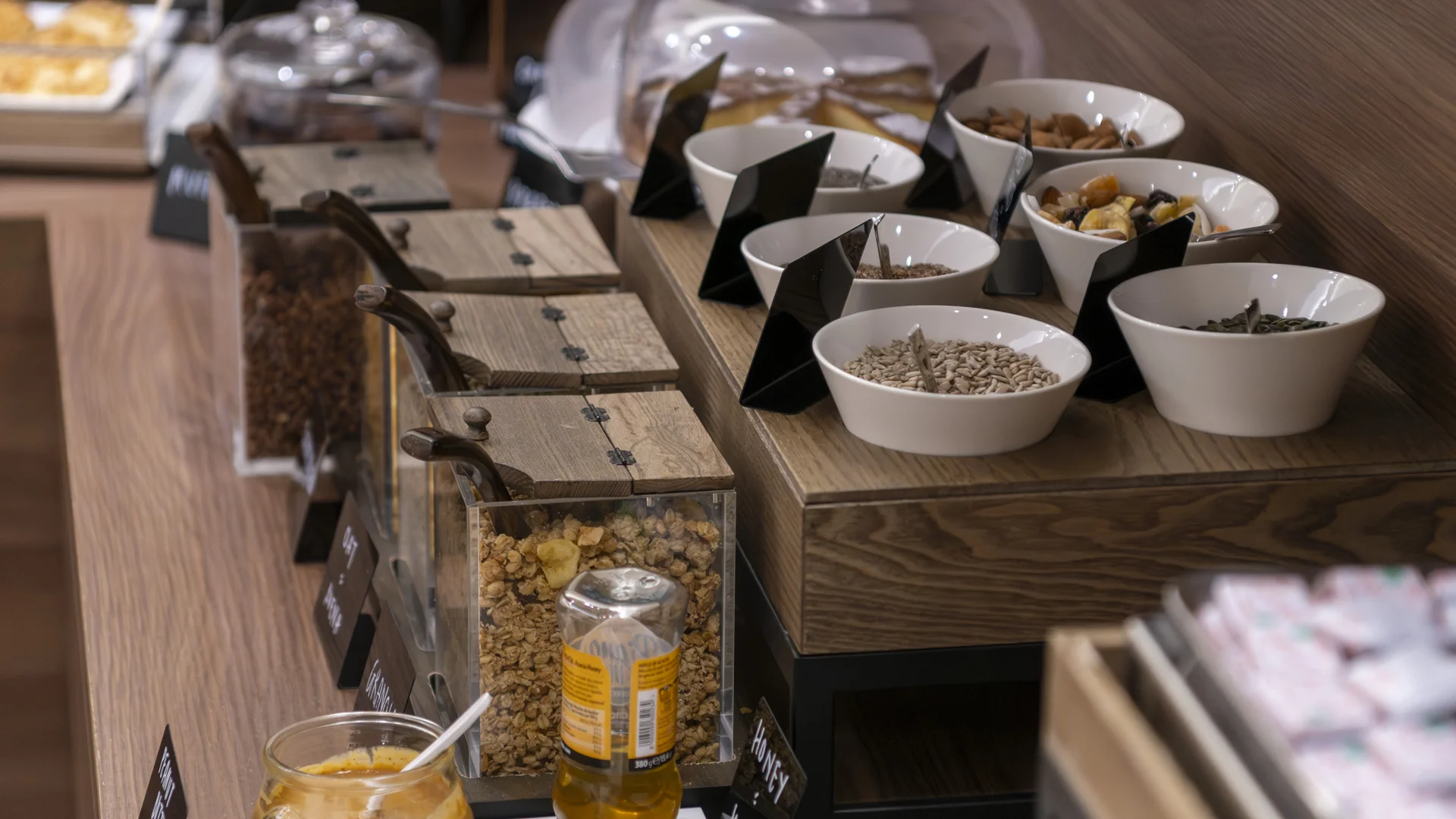 Hotel Touring in Verona | Picture gallery Buffet con cereali, semi, miele e dolci in contenitori di vetro e ciotole bianche