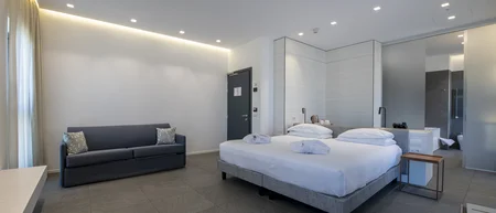 Camera d'albergo moderna con letto matrimoniale e divano grigio