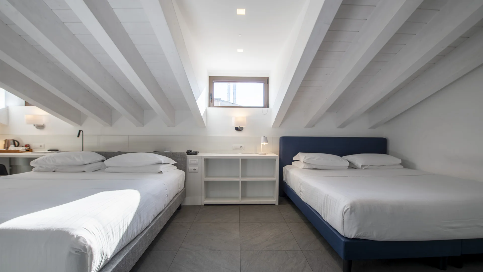 Hotel Touring in Verona | Picture gallery Camera con due letti matrimoniali sotto un soffitto inclinato con travi bianche