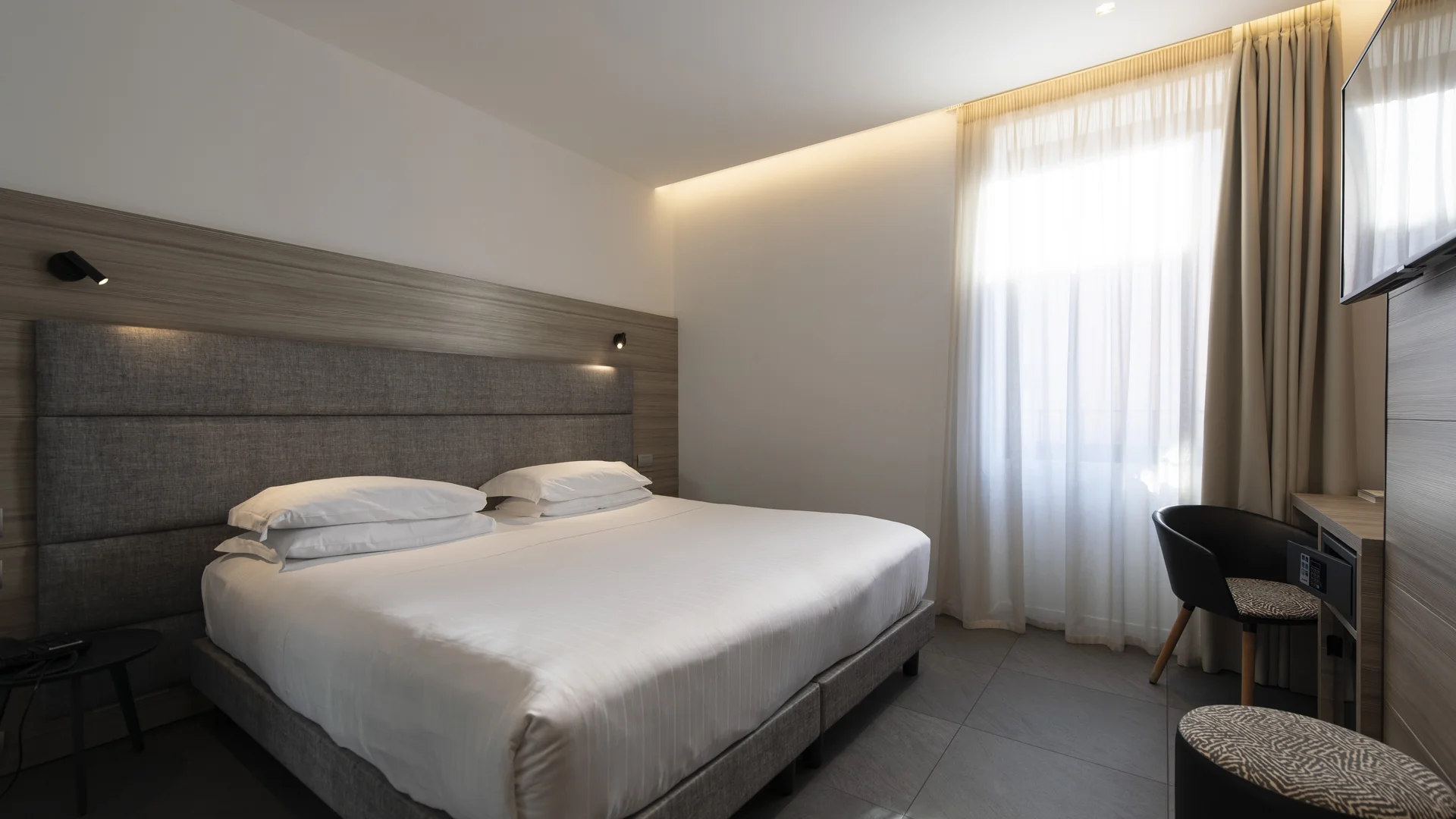 Hotel Touring in Verona | Picture gallery Camera d'albergo moderna con letto matrimoniale, scrivania e finestra con tende