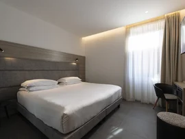 Camera d'albergo moderna con letto matrimoniale, scrivania e finestra con tende