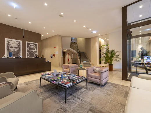 Reception di hotel con divani, tavolino e due grandi ritratti in bianco e nero