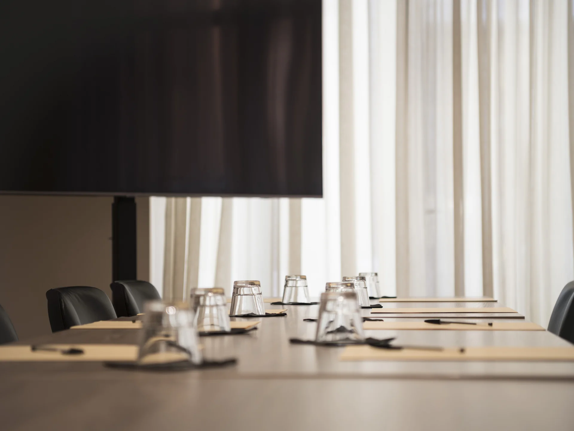 Konferenzraum mit Tisch, Stühlen, umgedrehten Gläsern und Stiften