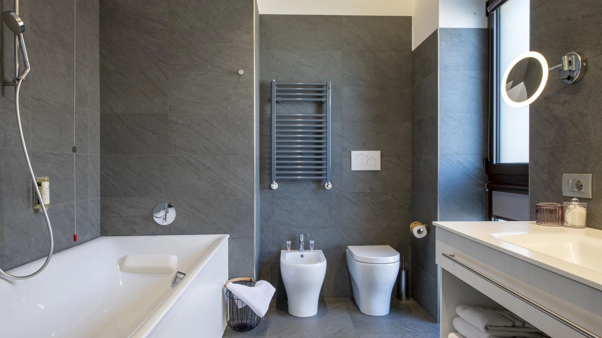 Hotel Touring in Verona | Picture gallery Bagno moderno con vasca, bidet, WC, lavabo e pareti grigie