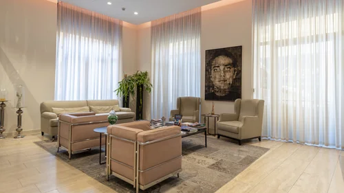 Hotel Touring in Verona | Picture gallery Salotto moderno con poltrone, divano beige e grande quadro in una stanza luminosa