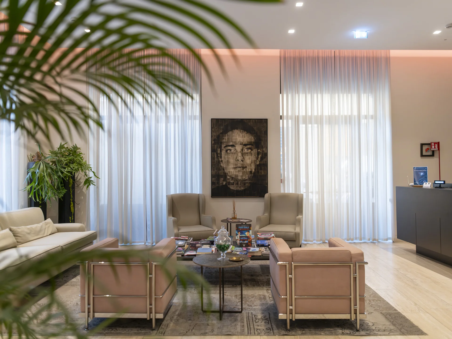 Sala d'attesa moderna con poltrone beige, divano e grande ritratto in bianco e nero